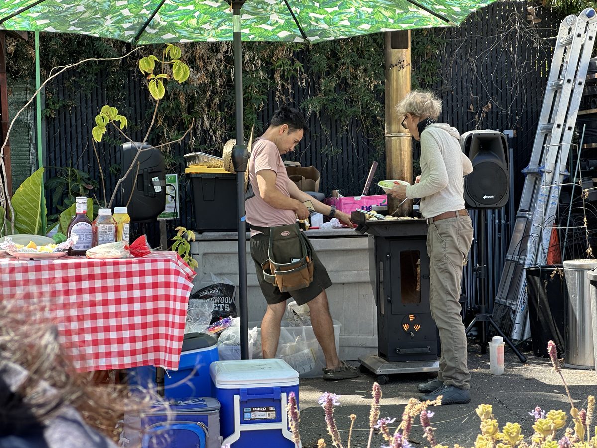 Neighbors cooking at a table under a green umbrella