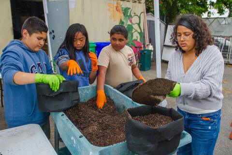 Kids filling fabric grow bags with soil